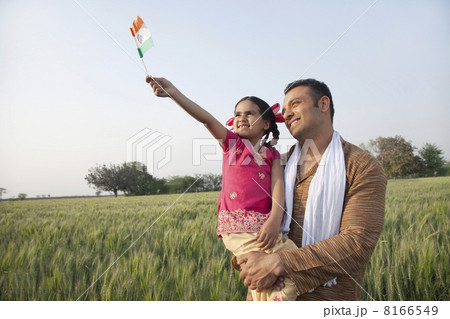 Man with his daughter holding Indian flag in an agricultural field Man with his daughter holding Indian flag in an agricultural field 8166549