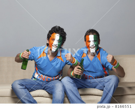 Portrait of male friends on sofa with painted face cheering while having drink at home Portrait of male friends on sofa with painted face cheering while having drink at home 8166551