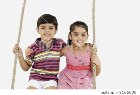 Portrait of boy and girl sitting on a swing 8166600