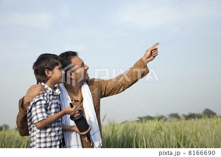 Father and son flying a kite in field 8166690