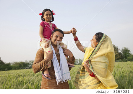 Family in field with girl on fathers shoulders 8167081