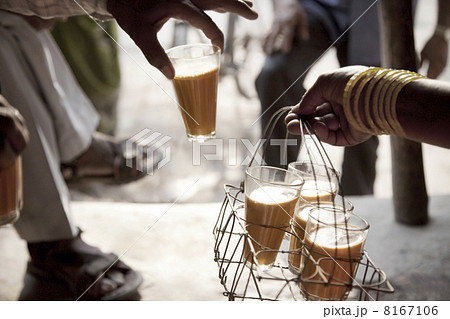 Male hand taking a glass of chai from tray held by woman Male hand taking a glass of chai from tray held by woman 8167106
