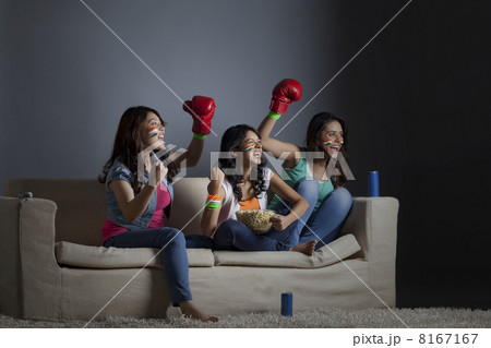 Cheerful young female friends watching boxing match together at home 8167167