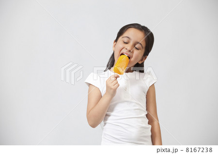 Happy little girl eating ice lolly isolated over gray background 8167238