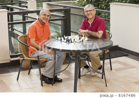 Portrait of happy senior men sitting around table with chess board 8167486