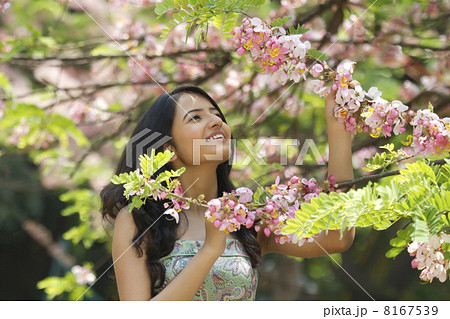 Young woman admiring flowers on a branch 8167539