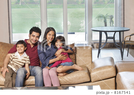 Portrait of happy Indian family of four sitting together on sofa 8167541