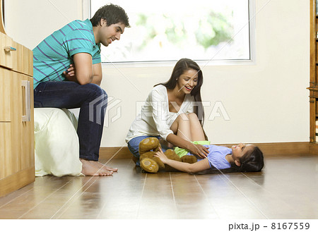 Happy woman playing with daughter while man sitting besides 8167559