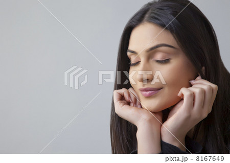 Close-up of a beautiful Indian young woman with eyes closed over colored background 8167649