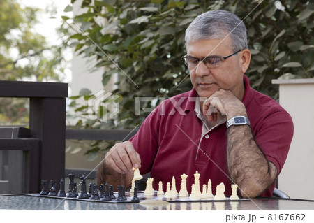 Senior man playing chess game while sitting by table 8167662