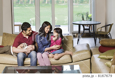 Happy young couple sitting with kids on sofa at home Happy young couple sitting with kids on sofa at home 8167679