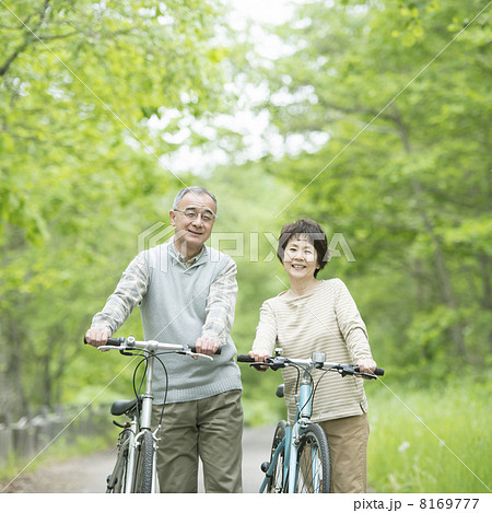 新緑の中で自転車を押すシニア夫婦 8169777
