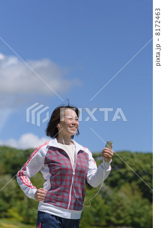 スマートフォンで音楽を聴きながらウォーキングする女性 8172463