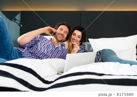 Young couple in Hotel in bed with phone and computer 8175980