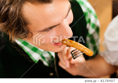 Man in restaurant or pub eating sausage 8176407