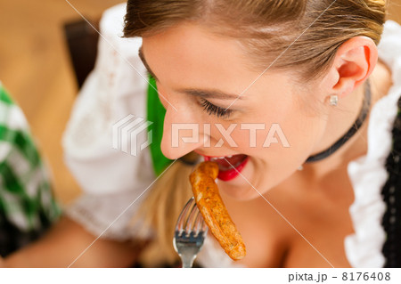 Woman in restaurant or pub eating sausage Woman in restaurant or pub eating sausage 8176408