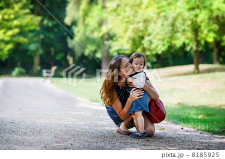 Beautiful mother and little daughter walking in summer park Beautiful mother and little daughter walking in summer park 8185925