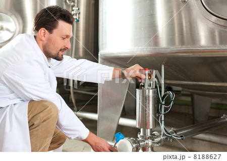 Beer brewer in his brewery at food tank 8188627