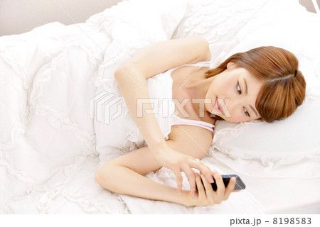 ベットでスマートフォンをする女性 8198583