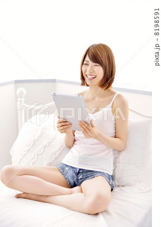 ベットの上でタブレットをする女性 8198591