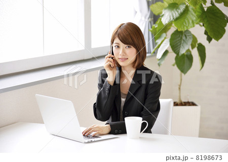 パソコンを見ながら電話をする女性 パソコンを見ながら電話をする女性 8198673