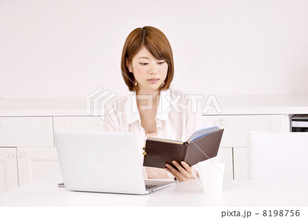 手帳を見ながらパソコンをする女性 8198756