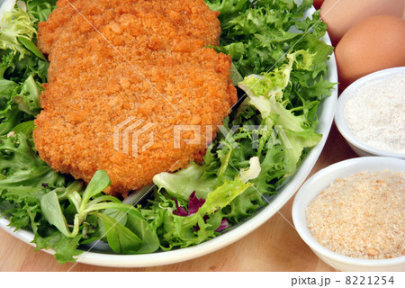 breaded cutlet with some organic salad on a plate 8221254