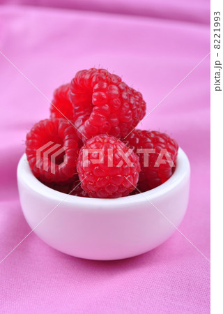some organic raspberries in a small white bowl some organic raspberries in a small white bowl 8221993