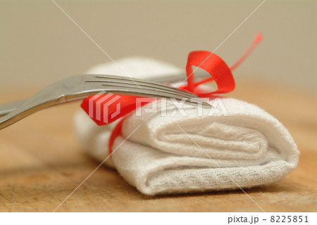 Fork and knife with a white serviertte and red ribbon Fork and knife with a white serviertte and red ribbon 8225851