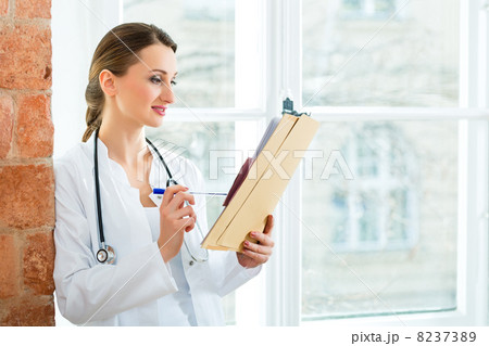 Doctor in clinic writing in a file Doctor in clinic writing in a file 8237389