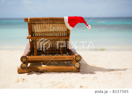 Santa hat on chaise longue on white sand beach Santa hat on chaise longue on white sand beach 8237565
