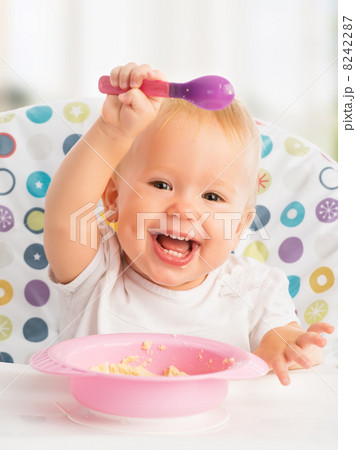 happy baby child eats itself with a spoon 8242287