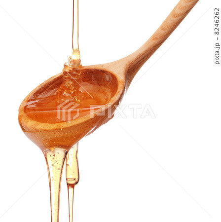 Honey dripping from a wooden honey dipper isolated on white back Honey dripping from a wooden honey dipper isolated on white back 8246262