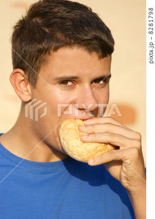 a male teenager eating a bread roll 8281798