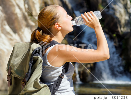 Young woman drinks water by waterfall 8314238