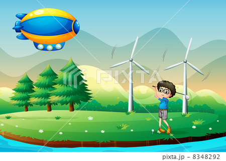 A boy playing golf in the field with windmills A boy playing golf in the field with windmills 8348292