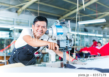Asian worker using a machine in a factory 8357179