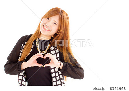 胸の前で手をハート型にして笑うキュートな女の子の写真素材