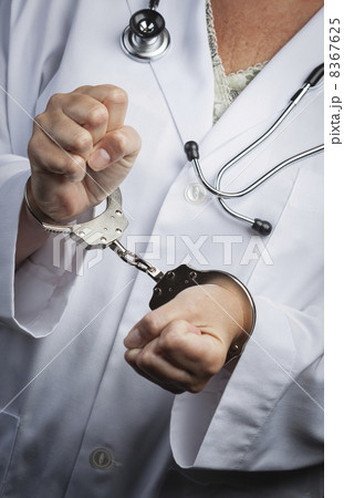 Doctor or Nurse In Handcuffs Wearing Lab Coat and Stethoscope 8367625