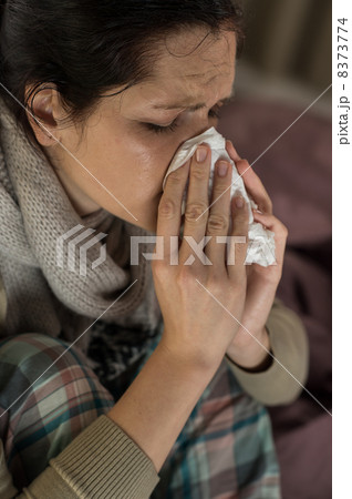 Portrait of woman sneezing into tissue 8373774