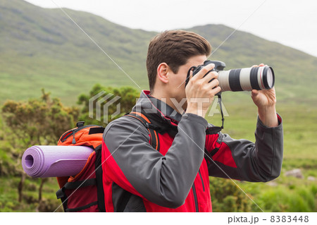 Sporty man on a hike taking a photograph 8383448