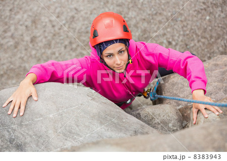 Smiling girl climbing up rock face Smiling girl climbing up rock face 8383943