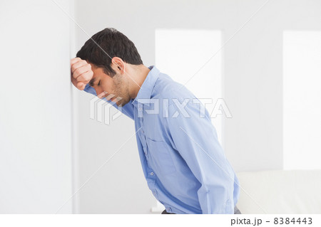 Sad man leaning his head against a wall 8384443