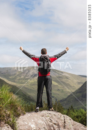 Man standing at hill top cheering Man standing at hill top cheering 8385035