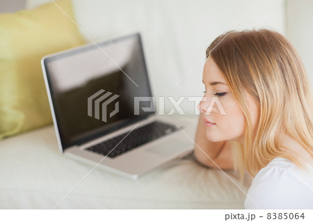 Thoughtful woman sitting on floor in front of laptop 8385064