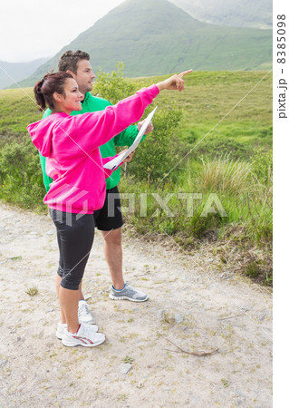 Couple holding a map and pointing ahead Couple holding a map and pointing ahead 8385098