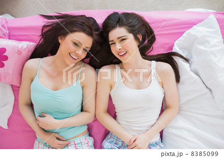 Smiling friends in pajamas looking at camera on bed Smiling friends in pajamas looking at camera on bed 8385099