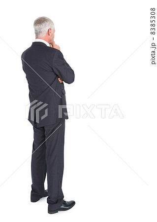 Thoughtful businessman standing back to camera Thoughtful businessman standing back to camera 8385308