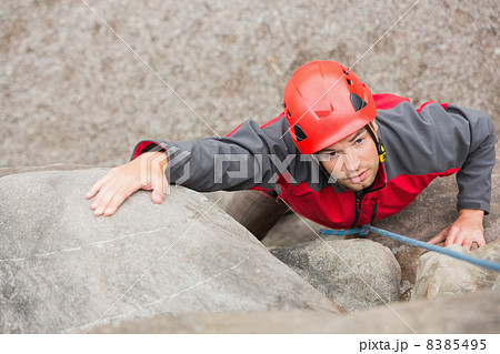 Determined man climbing rock face 8385495