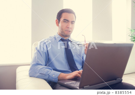 Nervous man biting his eyeglasses and using a laptop Nervous man biting his eyeglasses and using a laptop 8385554